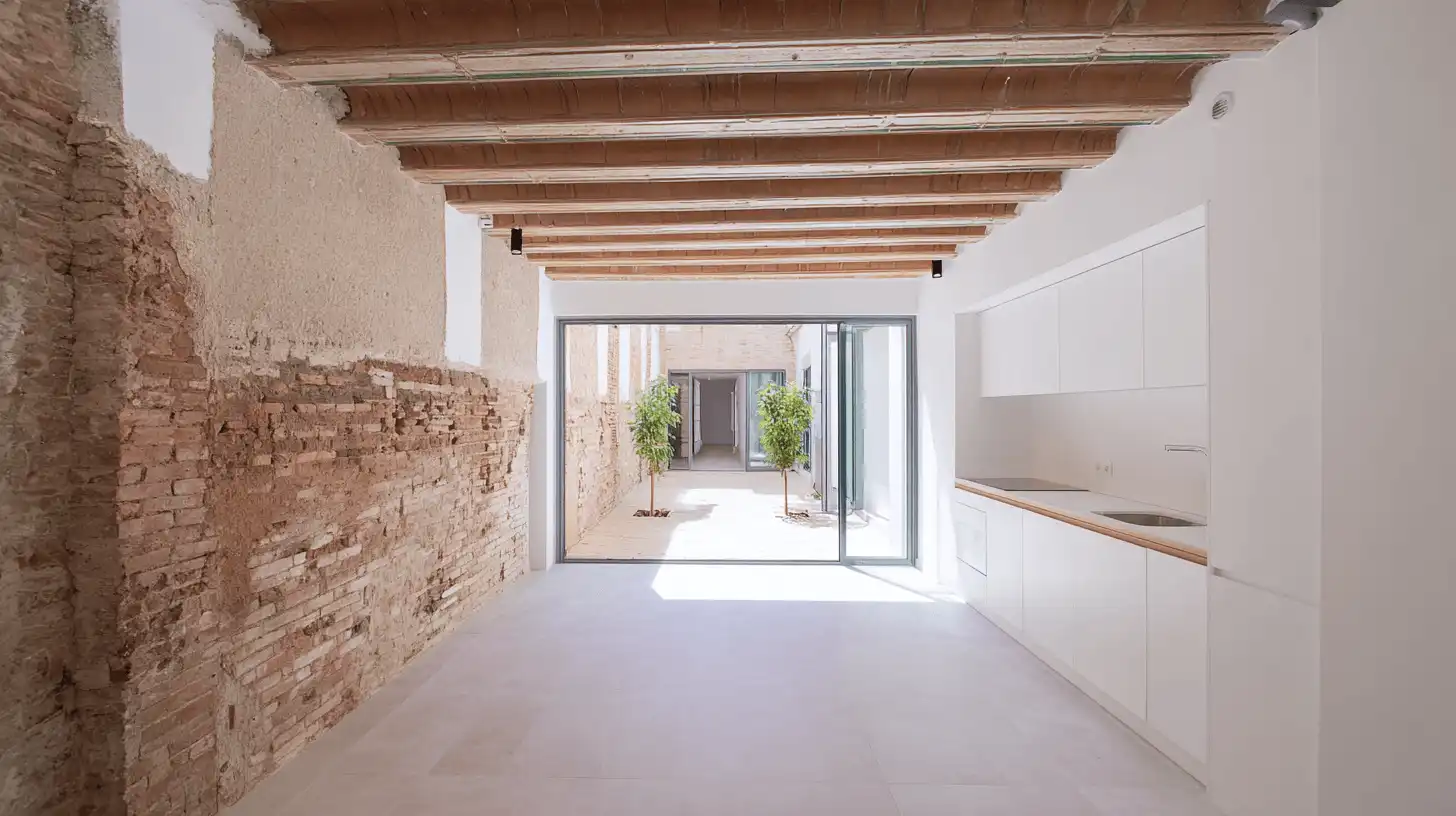 Casa de cos rehabilitada con pared de ladrillo visto, vigas de madera y patio interior en Sabadell